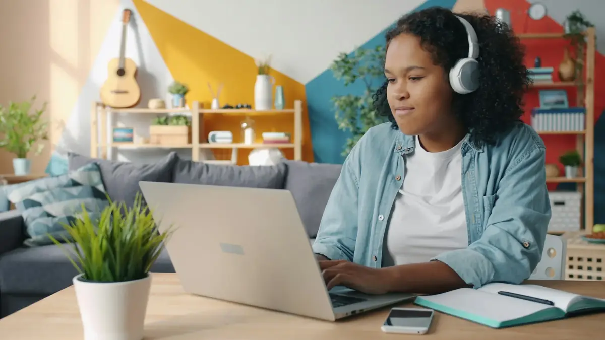 Murid mengikuti kelas daring dengan laptop dan headphone di meja belajar